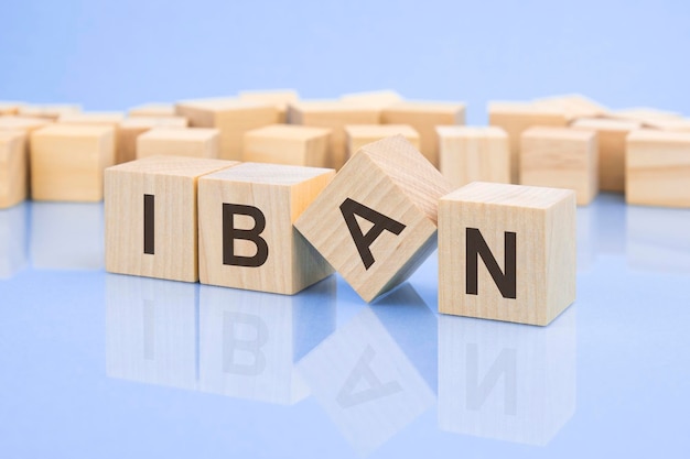 Cubes en bois avec les lettres IBAN sur la surface brillante d'une table lilas pâle l'inscription sur les cubes se reflète sur la surface du concept d'entreprise de table