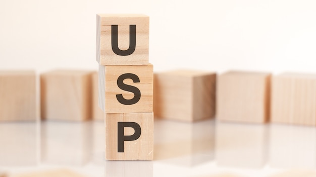 Cubes en bois avec lettres USP disposés en pyramide verticale, sur fond clair, surface de réflexion, concept