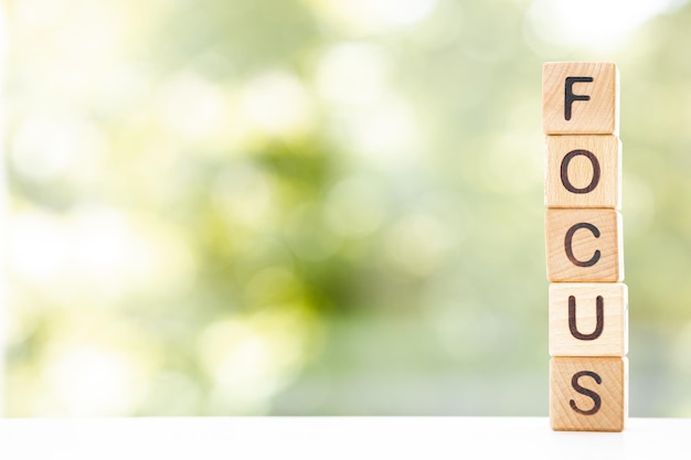 Les cubes en bois se trouvent sur une table sur un fond vert Les cubes composent le mot FOCUS