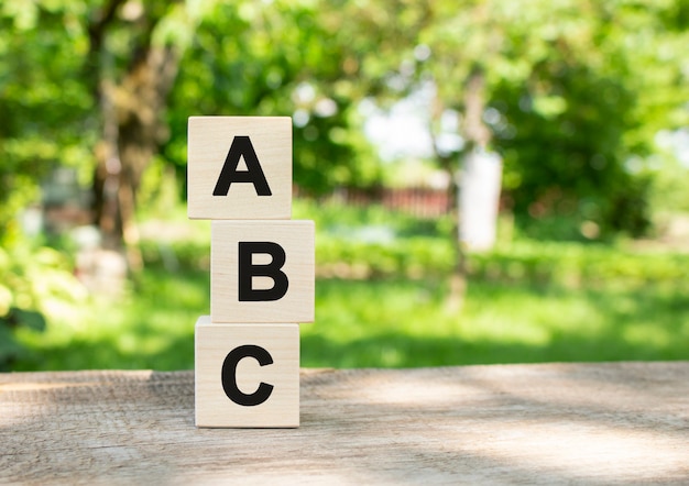 Des Cubes En Bois Sont Empilés Verticalement Sur Une Table En Bois Dans Le Jardin. Le Mot Abc Est écrit En Lettres Noires.