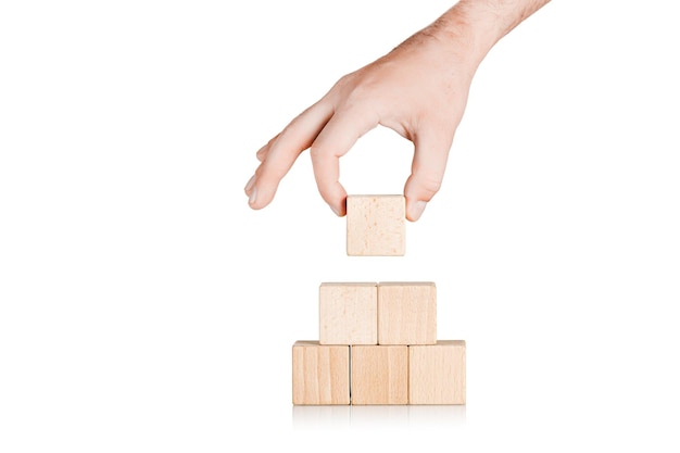 Photo cubes en bois sous la forme d'une pyramide avec une main sur un fond blanc isolé en gros plan