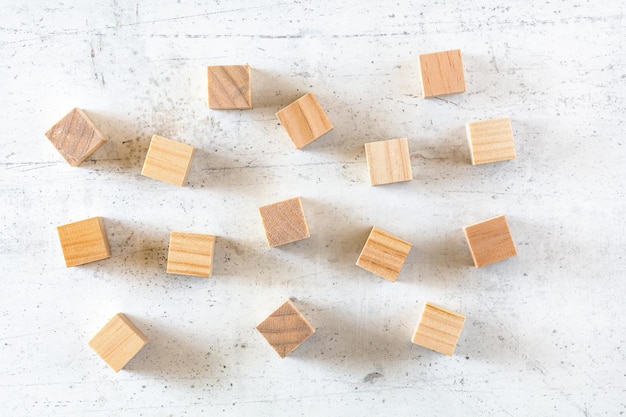 Cubes en bois vierges éparpillés sur une planche en pierre blanche, photo à plat.