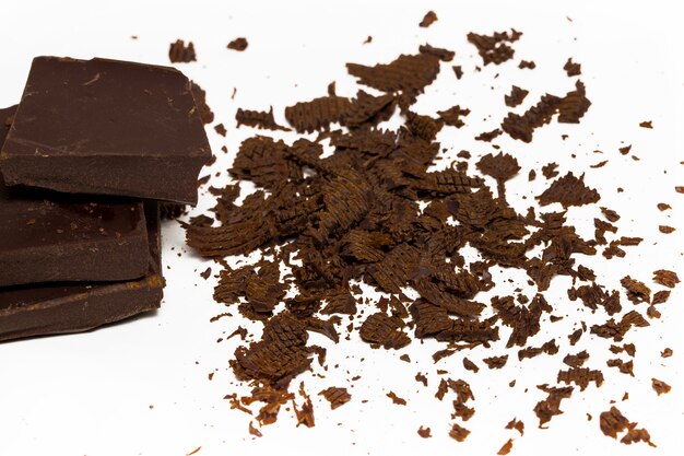Photo cubes de chocolat, morceaux de barre de chocolat amer et noir, isolés sur fond blanc, vue de dessus.