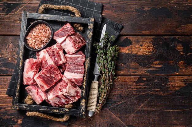 Cubes crus non cuits en dés de viande d'agneau dans un plateau en bois avec du sel et du thym Fond en bois Vue de dessus Espace de copie