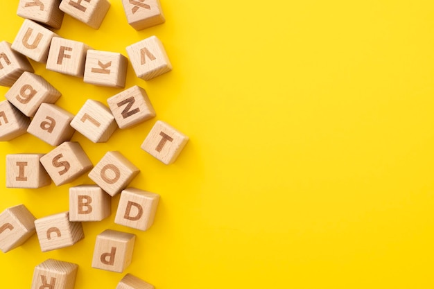 Cubes éducatifs en bois avec des lettres sur la surface portant sur fond jaune