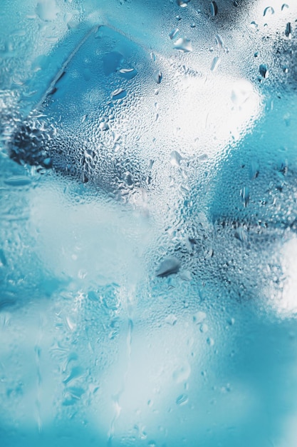 Cubes de glace dans un verre embué avec des gouttes de macro gros plan d'eau glacée. Mise au point sélective douce