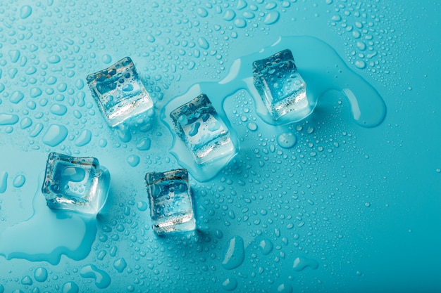 Photo cubes de glace avec des gouttes d'eau dispersées, vue de dessus.