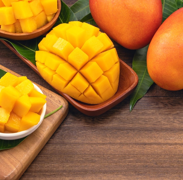 Cubes de mangue fraîche hachée sur planche à découper en bois et fond de bois rustique Concept de fruits d'été tropicaux gros plan macro copie espace