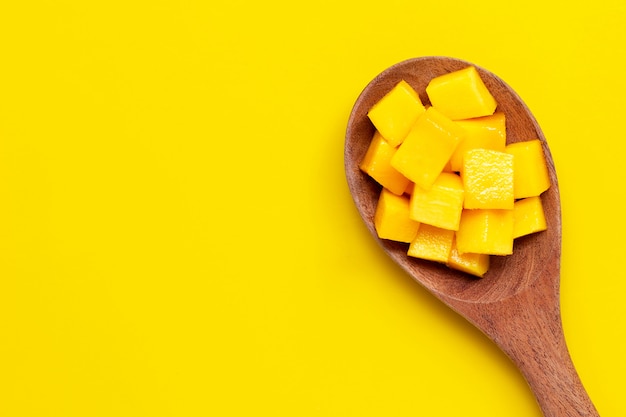 Cubes de mangue mûre en tranches sur une cuillère en bois