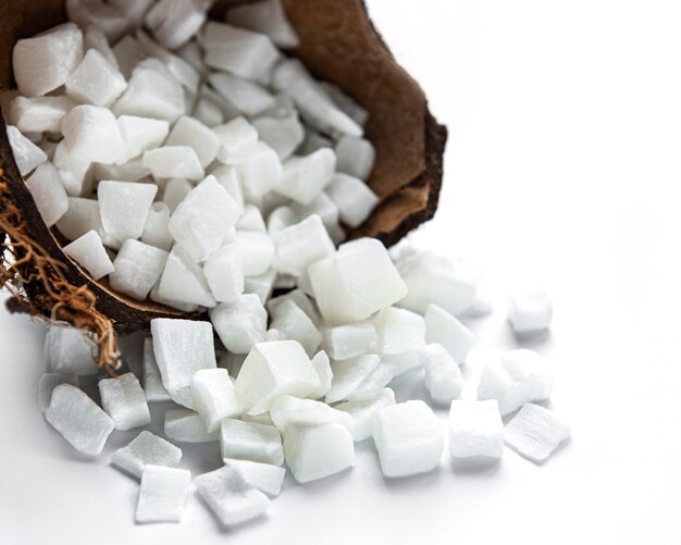 Cubes de noix de coco séchées dans un bol sur fond blanc.