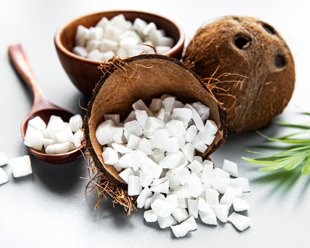 Cubes de noix de coco séchées dans un bol sur une surface blanche.