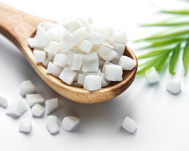 Cubes de noix de coco séchées dans une cuillère sur une surface blanche