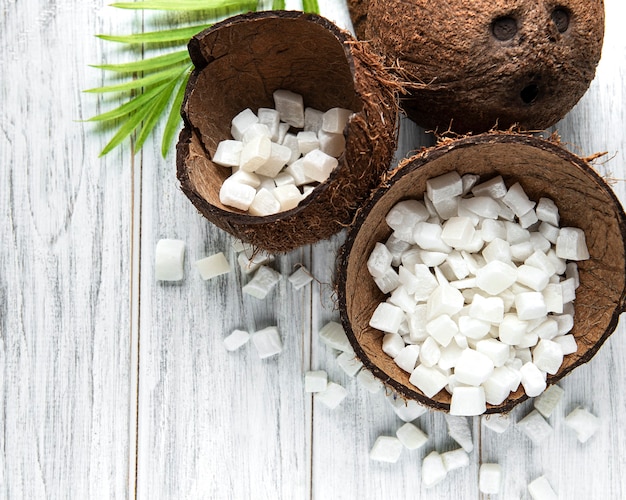 Cubes de noix de coco sucrée séchée dans un bol sur fond de table en bois.