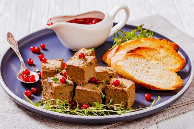 Cubes de pâté de foie sur assiette avec pain grillé et baies