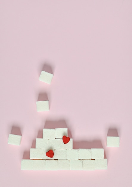 Cubes de sucre blanc sur un fond rose. Quels sont les concepts de diabète et d’apport calorique
