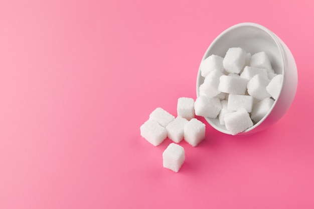 Cubes de sucre dans un bol sur fond rose