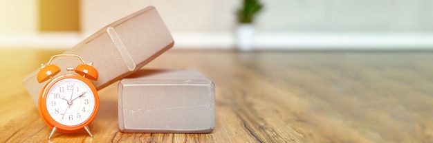 Cubes de support gris pour le yoga sportif ou les étirements et réveil sur le plancher en bois