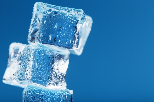 Cubes de tour de glace fondante sur fond bleu. Espace libre