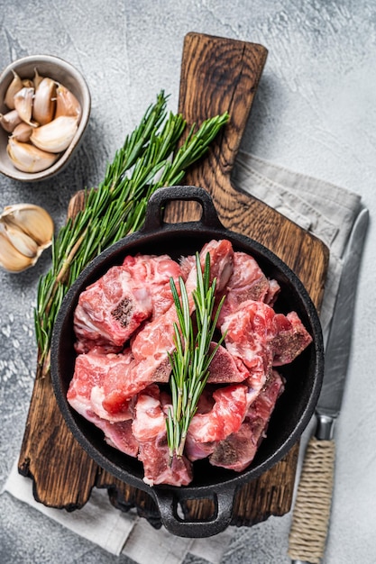 Cubes de viande en dés crus avec os dans une casserole. Fond blanc. Vue de dessus.