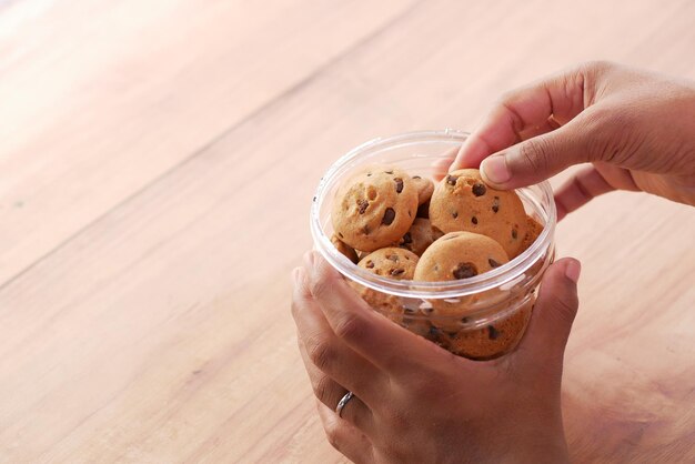 Cueillette à la main des cookies aux pépites de chocolat sur la table en gros plan