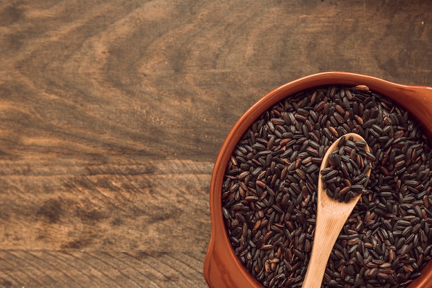 Photo cuillère en bois dans un bol de grain de riz brun sur une table en bois