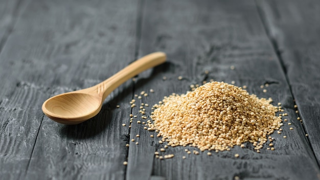 Cuillère en bois dans un tas de graines de quinoa sur une table en bois rustique.