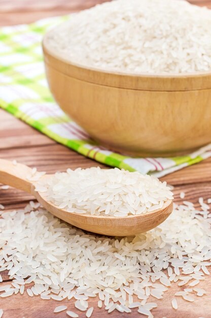 Cuillère en bois avec du riz et un bol de riz sur une table en bois