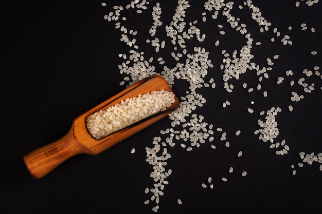 Cuillère en bois avec du riz sur une surface noire