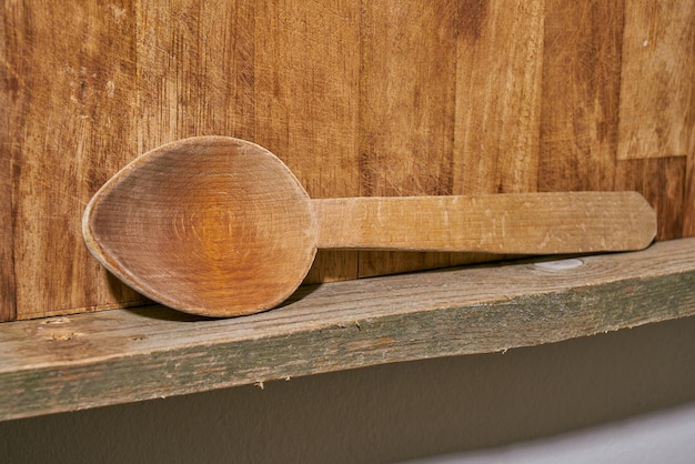 Cuillère en bois faite à la main sur une étagère de cuisine en bois.