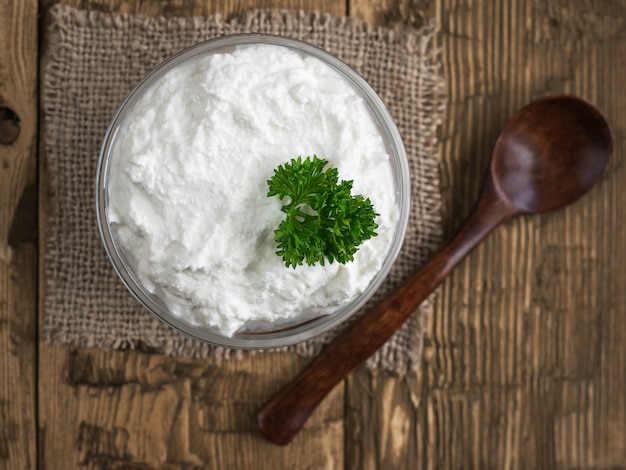 Cuillère de bois foncé et bol avec le fromage à la crème.