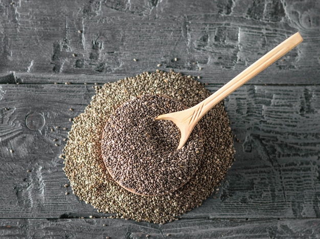 Cuillère en bois avec des graines de Chia sur une table rustique noire. La vue d'en haut. Mise à plat.