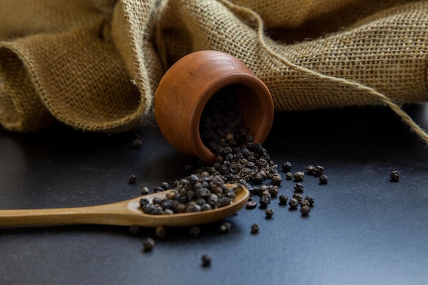 Une cuillère en bois avec des graines de poivre noir