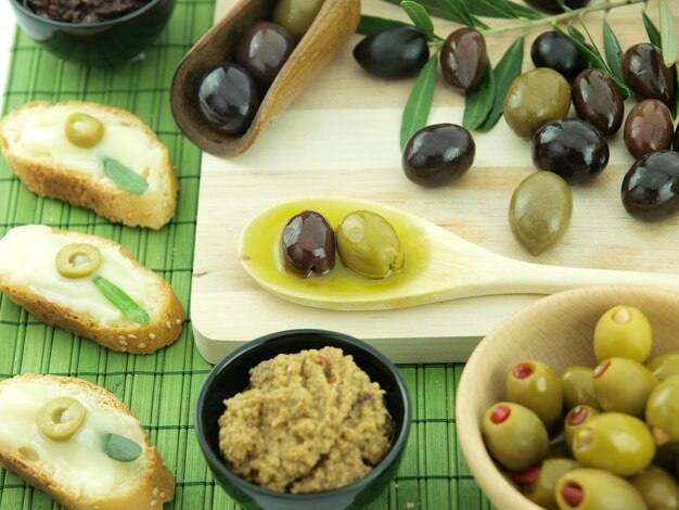 Une cuillère en bois avec des olives et un bol de houmous.