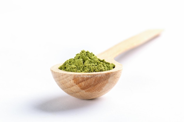 Photo cuillère en bois remplie de poudre de thé matcha japonais vert sur fond blanc