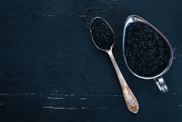 Cuillère à caviar noir sur fond de bois Vue de dessus Espace libre pour le texte