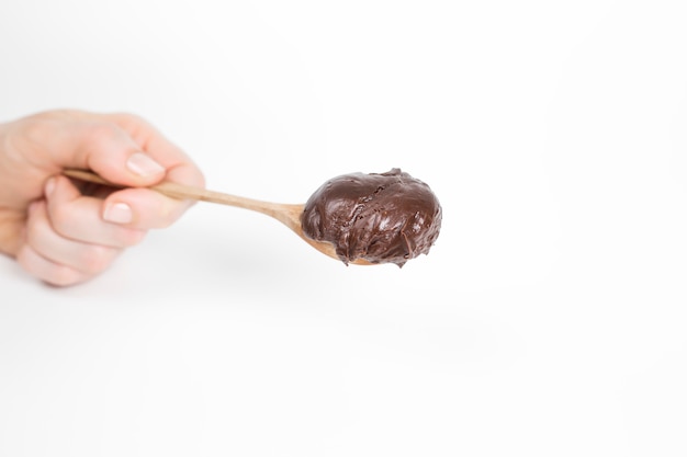 Cuillère de crème au chocolat sur un fond blanc.