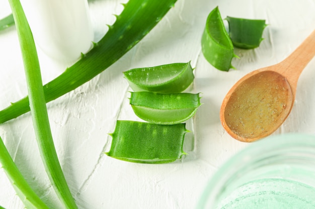 Cuillère à crème, feuilles d'aloe vera et tranches sur tableau blanc