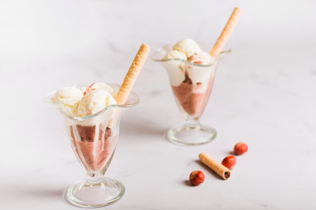 Cuillère à crème glacée dans un bol en verre avec paille gaufrée et noix