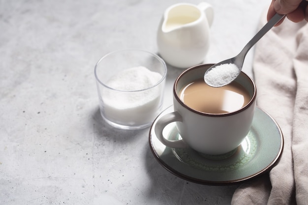 Cuillère avec édulcorant sur une tasse de café au lait