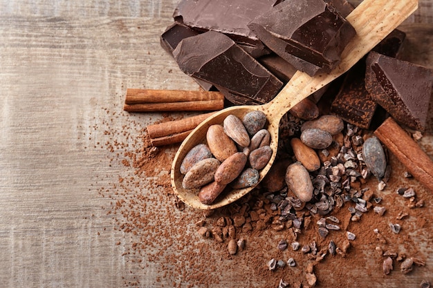 Cuillère à fèves de cacao et chocolat sur fond de bois