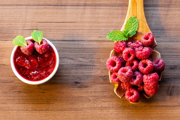 Cuillère à la framboise et bol avec confiture de framboise sur fond de bois,