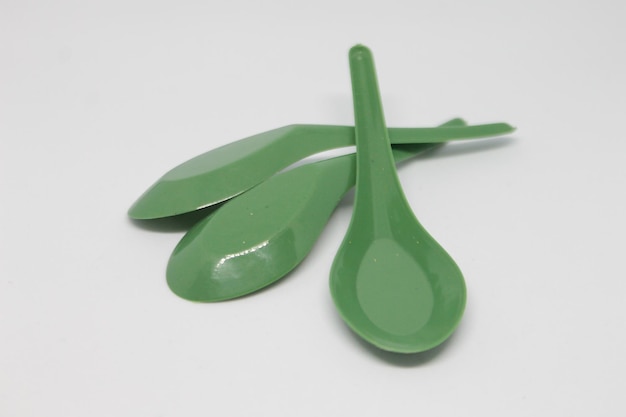 Une cuillère en plastique verte avec des feuilles dessus