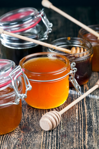 Photo une cuillère pour le miel avec du miel d'abeille de haute qualité, une vieille table sur laquelle se trouve un miel d'abeille sain et sucré et une cuillère en bois maison qui vous permet de transférer et de verser le miel