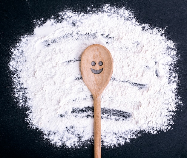 Cuillère Avec Un Visage Souriant Sculpté Se Trouve Sur De La Farine Dispersée