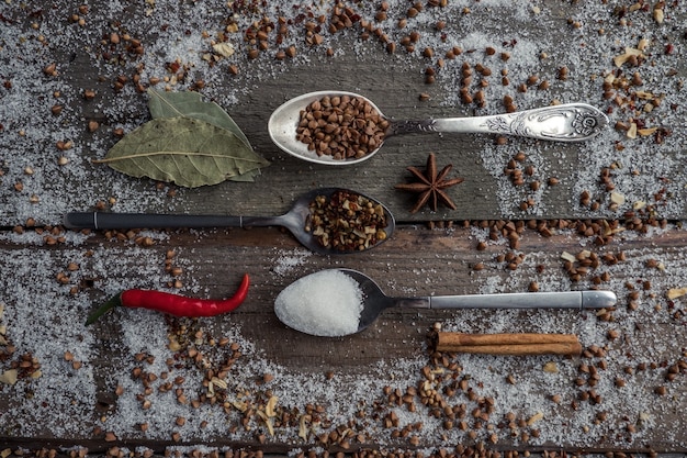 Photo cuillères d'assaisonnements sur une table en bois avec des assaisonnements éparpillés dessus