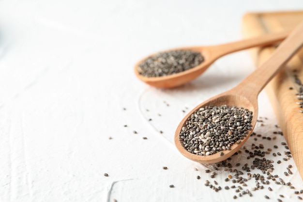 Cuillères en bois avec chia et planche sur blanc