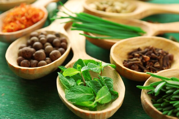 Photo cuillères en bois avec des herbes fraîches et des épices sur fond de bois