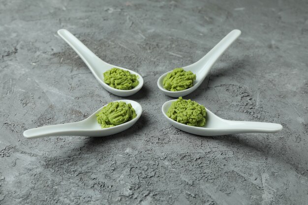 Cuillères en céramique avec wasabi sur fond texturé gris