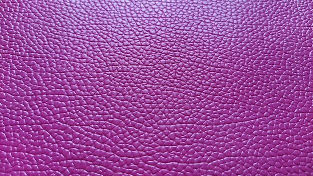 Le cuir artificiel est rose vif ou fuchsia Sillons et élévations distincts à la surface d'un sac ou d'une chaussure Reflet de la lumière Accessoire de mode en imitation peau de porc Gros plan