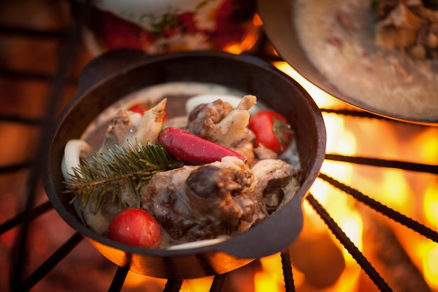 Cuire un plat de viande avec des branches d'épinette au bûcher